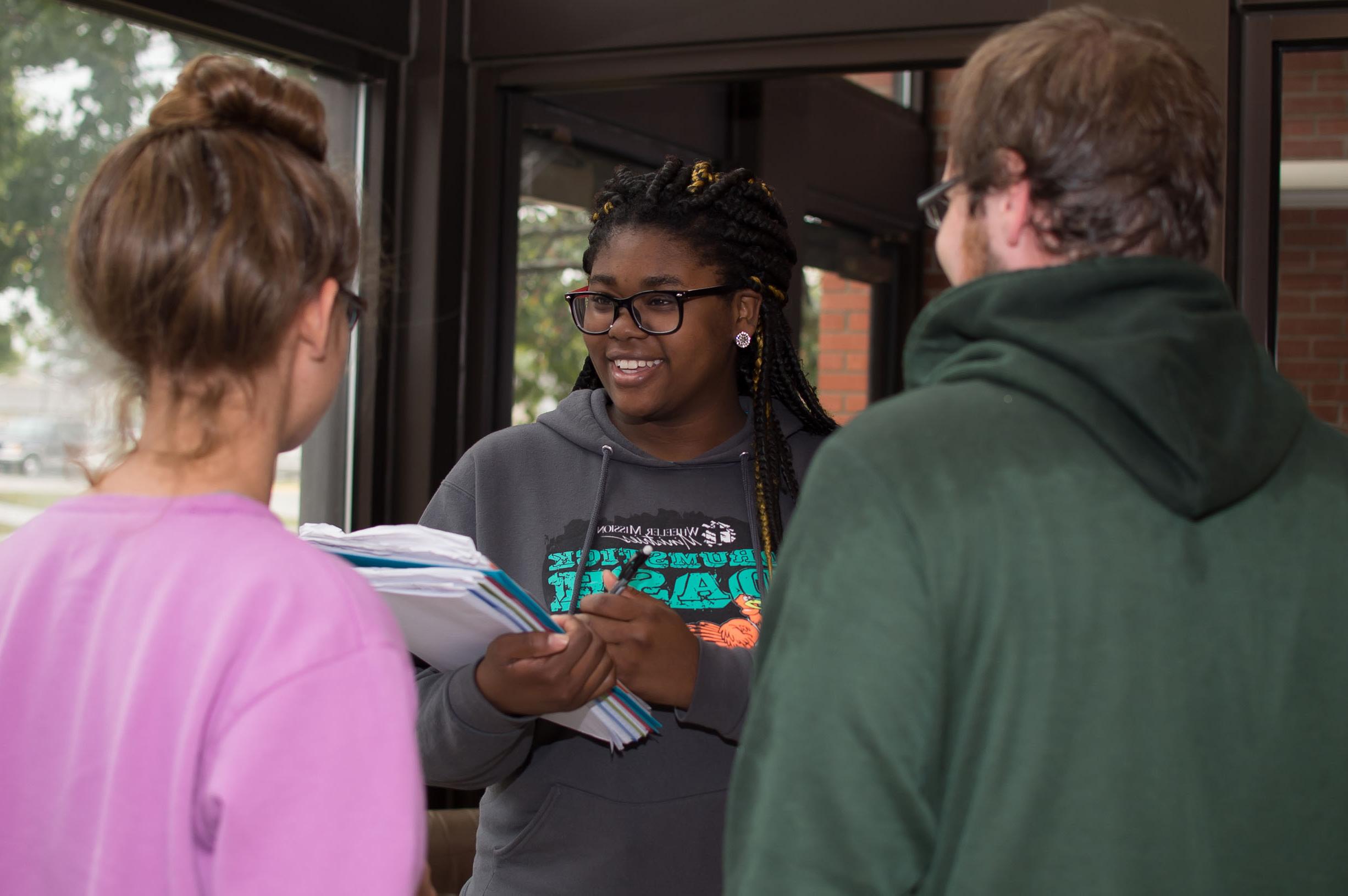 A public relations student talking to two other students