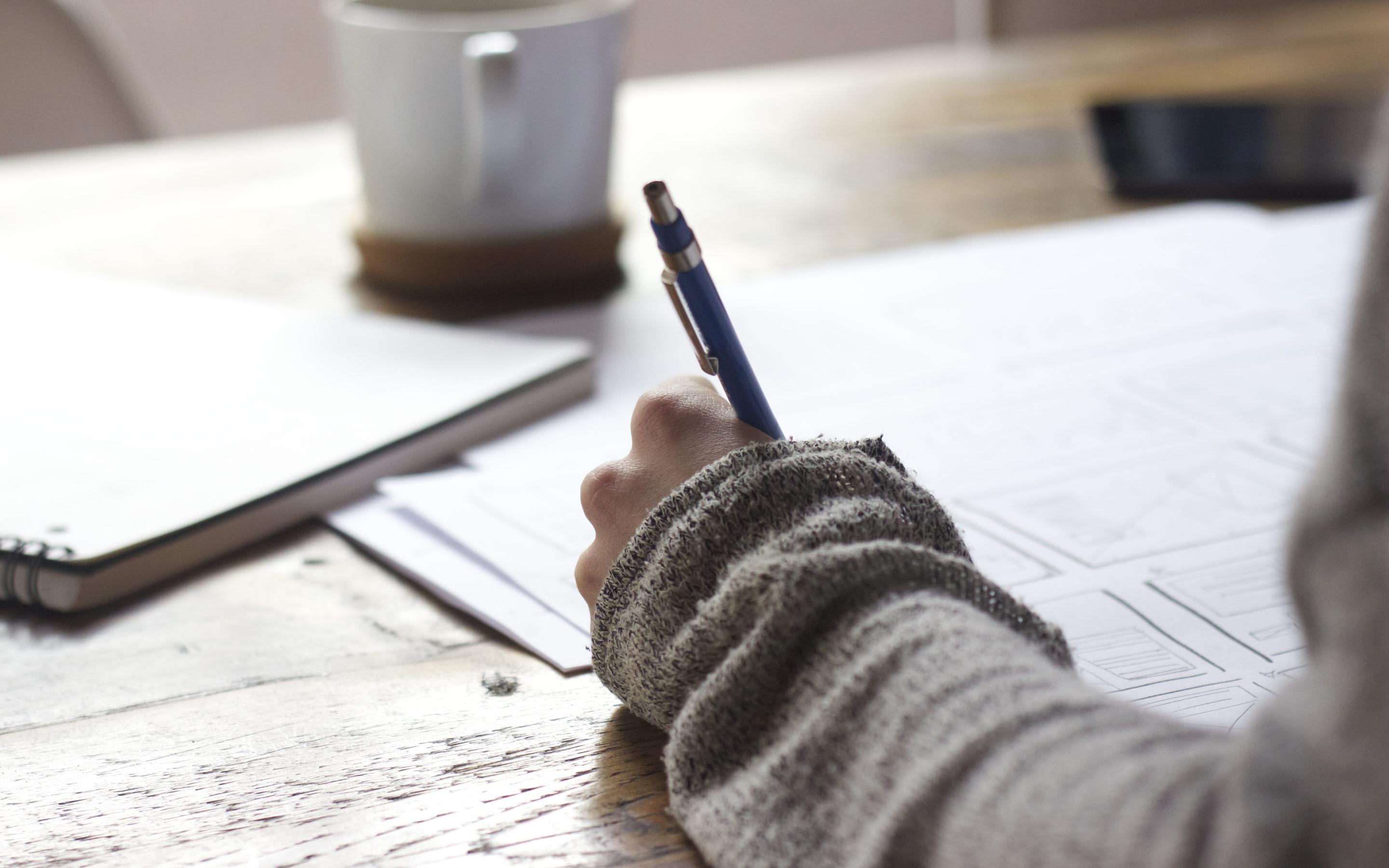 A student using a pen to complete their homework at their desk